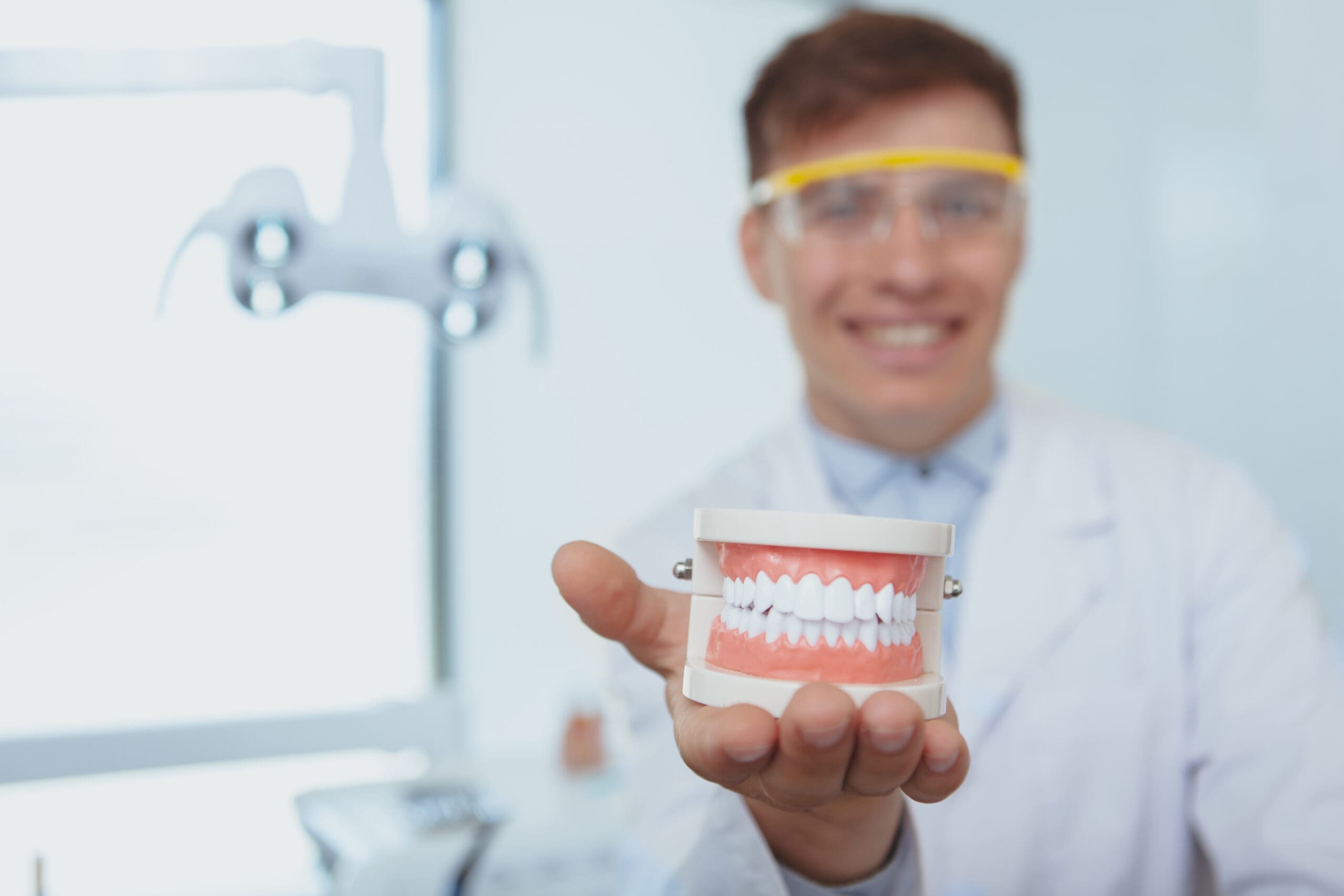 Smiling dentist holding a model of dentures, showcasing options for people with dentures to restore their smile and improve oral health.