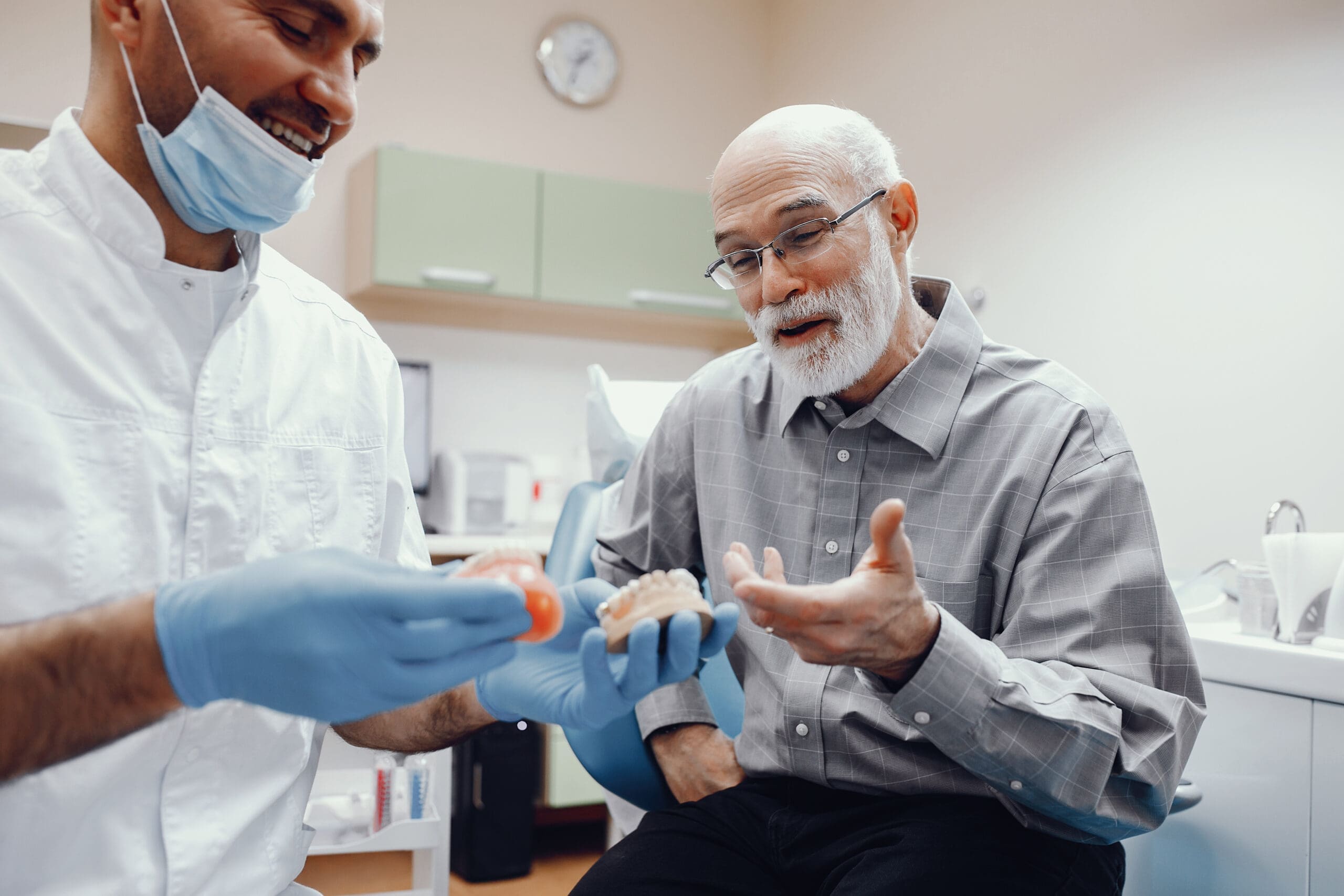 Elderly man consulting with a dentist about custom dentures, discussing personalized fit and comfort for a natural-looking smile.