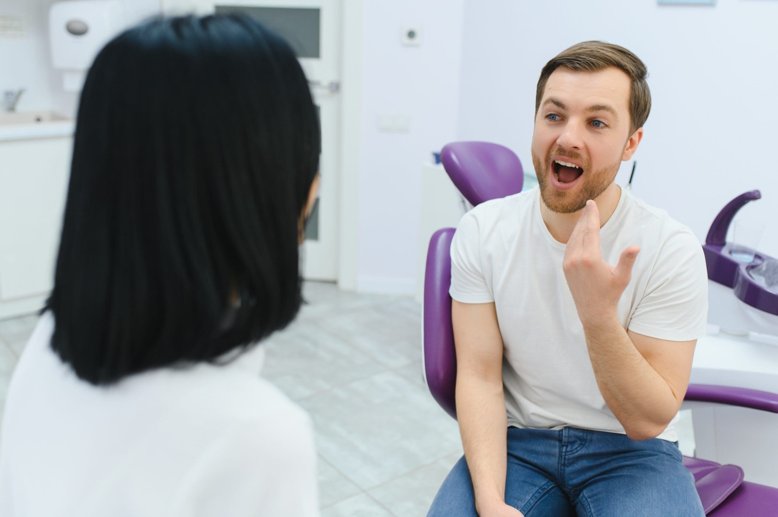 Young man consulting with a dentist, discussing the process of getting dentures and evaluating treatment options for a restored smile.